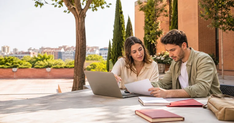 Dos estudiantes universitarios revisando ayudas en un campus de Madrid